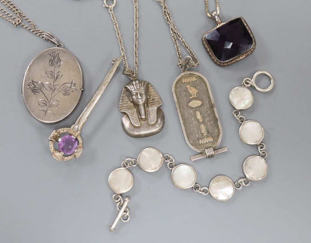 A silver locket on chain, a silver bracelet and other jewellery.